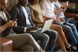 row of people sitting and working on laptops and phones