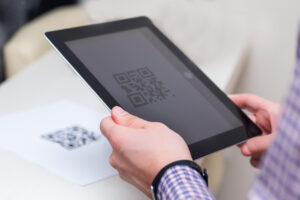 hands holding a tablet showing a large QR code