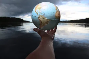 hand holding a globe out over calm water