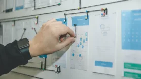 hand drawing lines between designs on a whiteboard